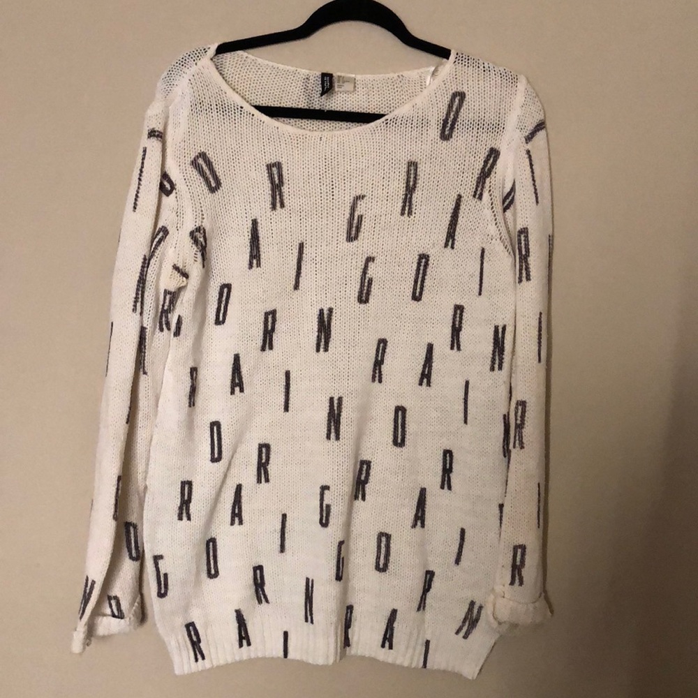 white and black knit sweater (Spells out “DARING”)